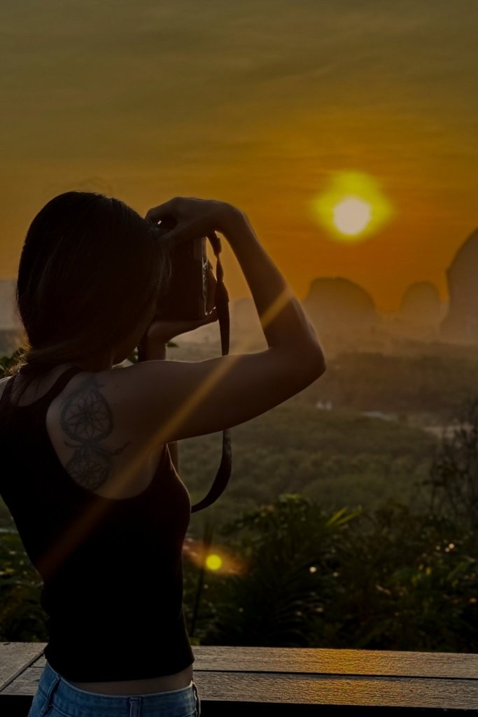 Female photographer taking photos at sunrise in Krabi Thailand with mountain landscape.